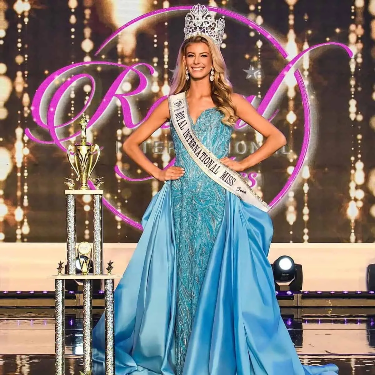 Ilané Liebenberg crowned on the Royal International Miss stage, in a sky-blue gown beside her trophy