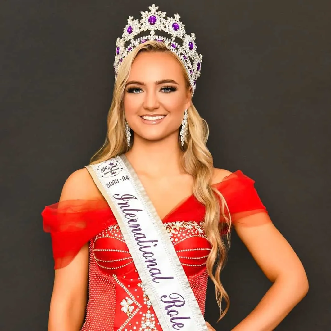 Immegan Erasmus wearing her crown and International Role Model sash, in a red gown