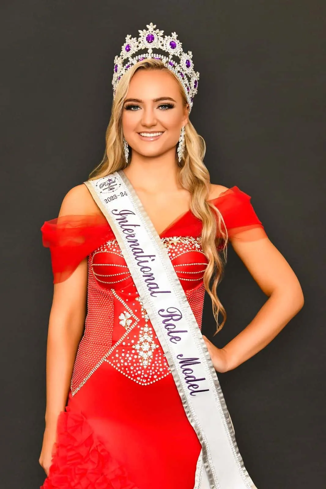 Immegan Erasmus wearing her crown and International Role Model sash, in a red gown