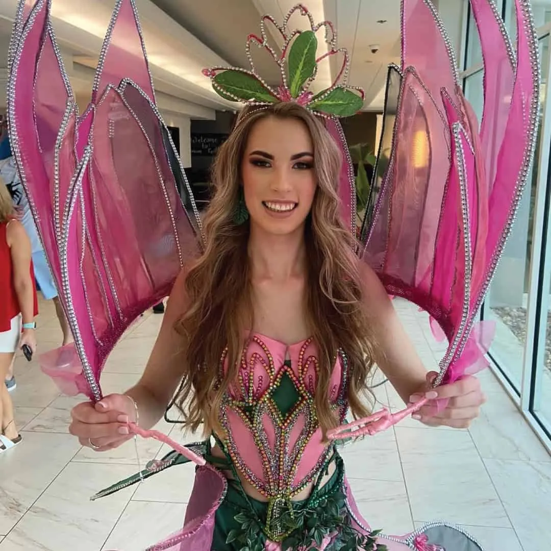 A delegate in a national costume with pink petal wings